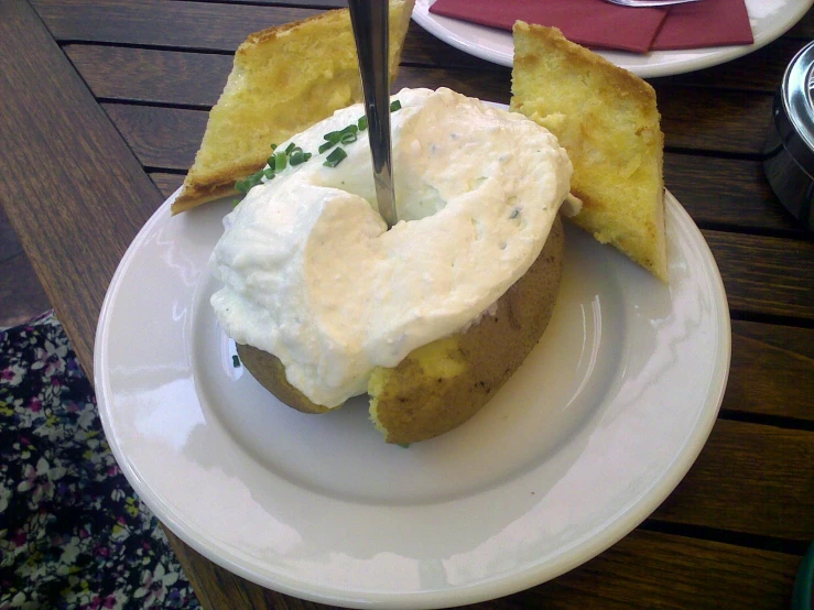 a white plate topped with a piece of bread and covered in cream