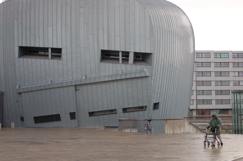 the person is hing their walker past a gray building