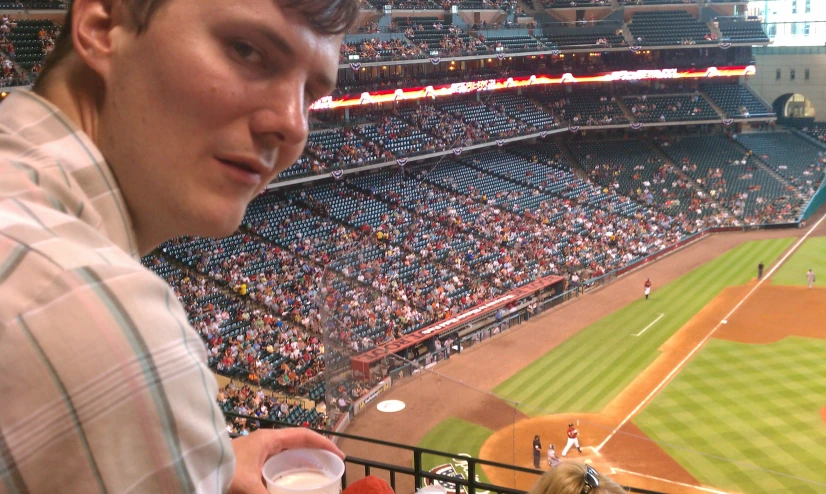 a man with a paper in his hand next to a baseball field