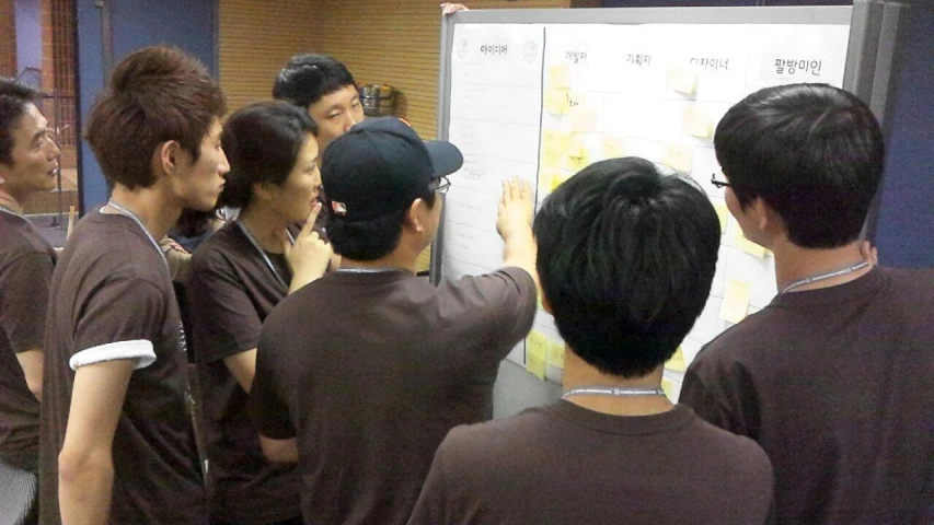 several people standing around a white board writing on it