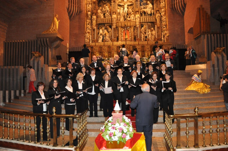 a conductor stands with his arms outstretched while other choir members stand in front of the choir