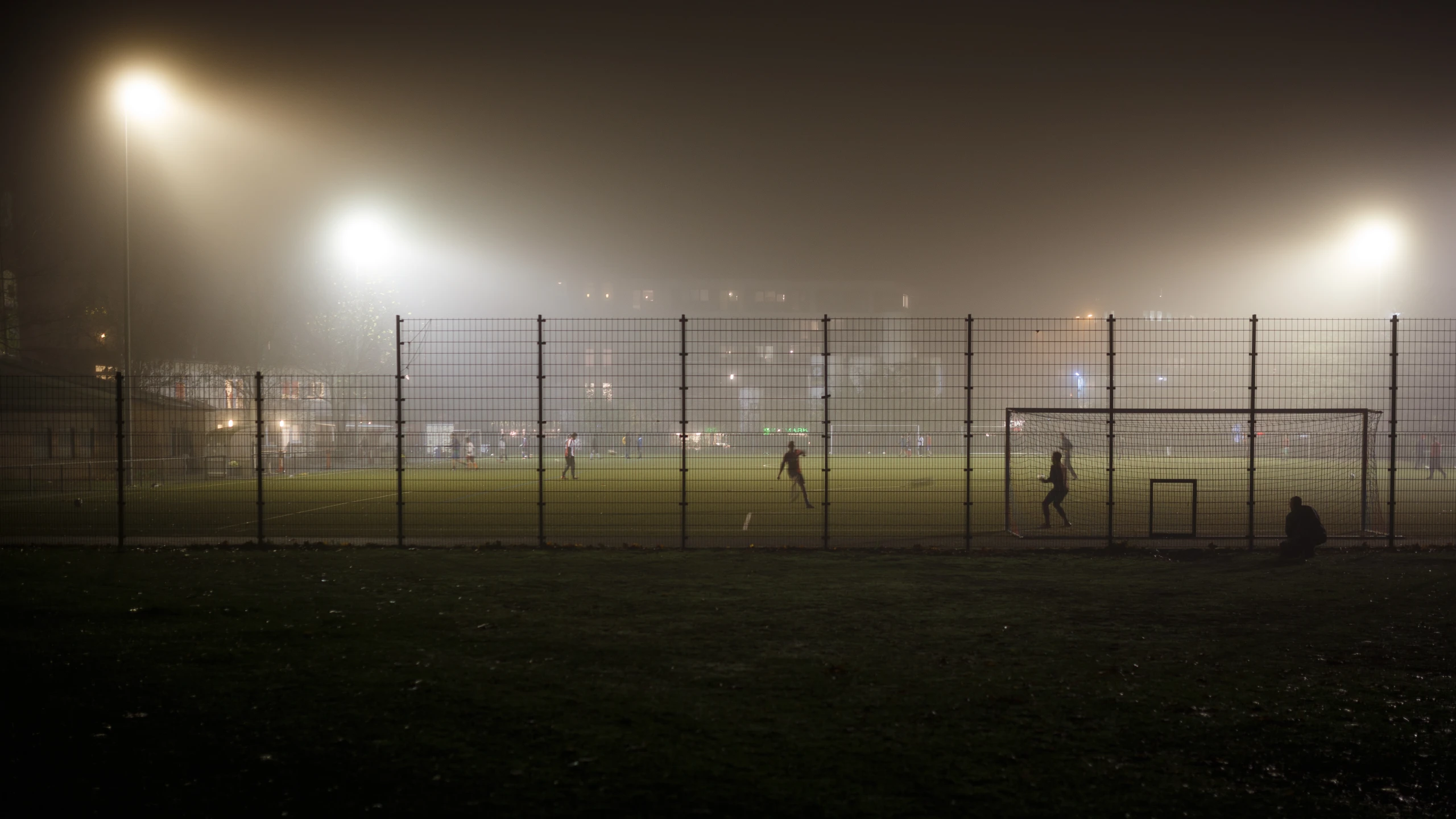 people playing baseball on a foggy field at night