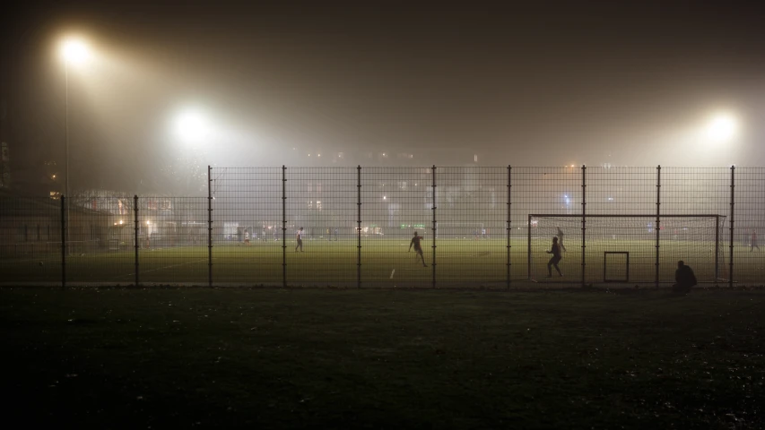 people playing baseball on a foggy field at night