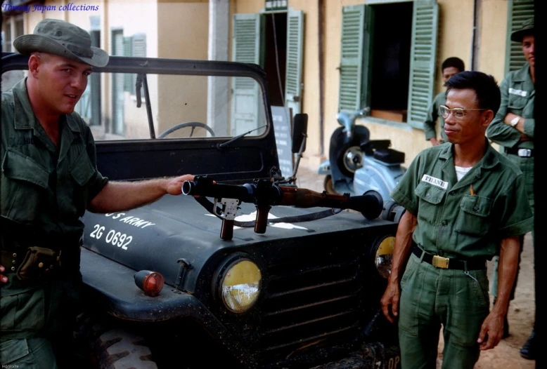 a man putting a fuel in to a vehicle and another man standing near by