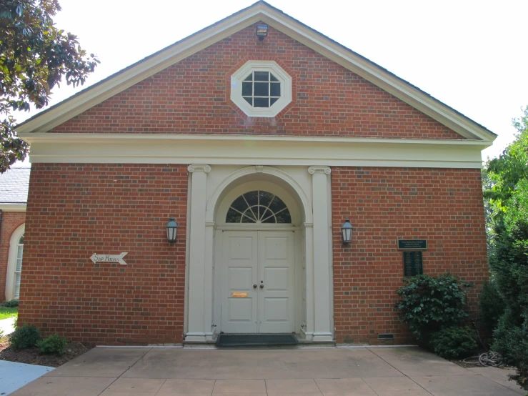 a brick building has a white door and arched window