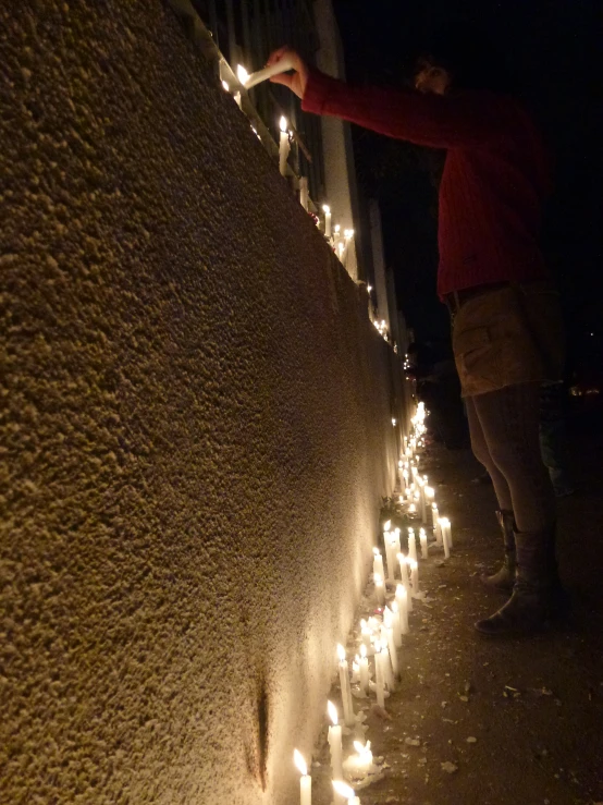 a person putting candles in the wall with the word light to the side
