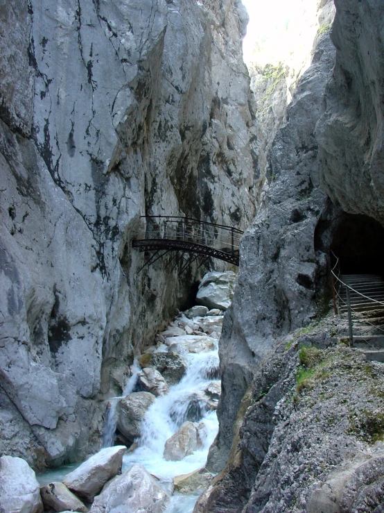 an narrow mountain has a bridge crossing over a river