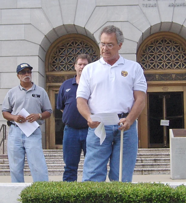 two men standing behind a street sweeper outside a building