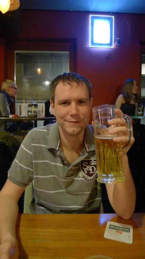 a man sitting at a table holding a glass of beer