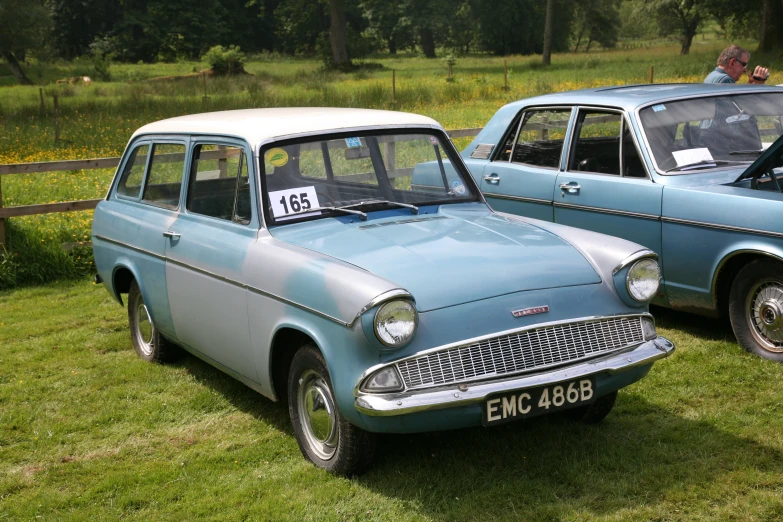 the old blue cars are parked on the grassy field