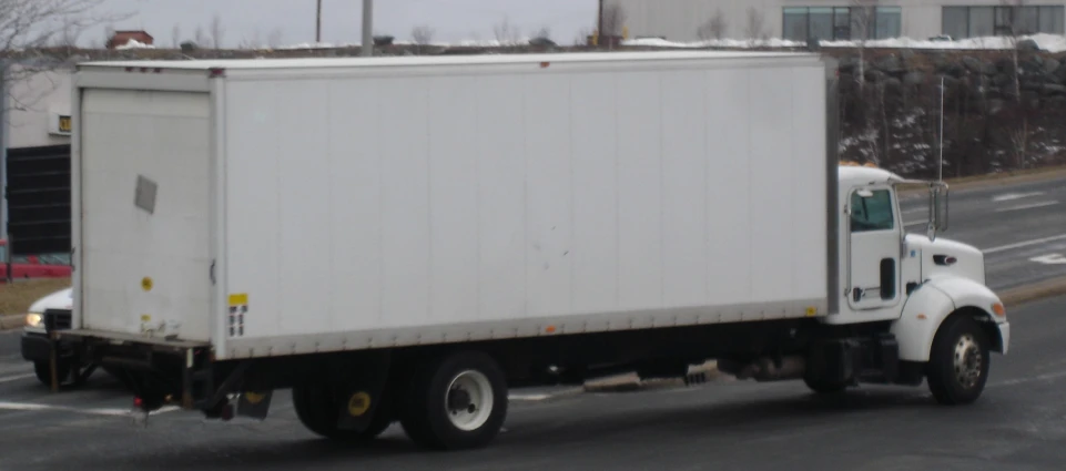 a white truck driving down a street next to a red car