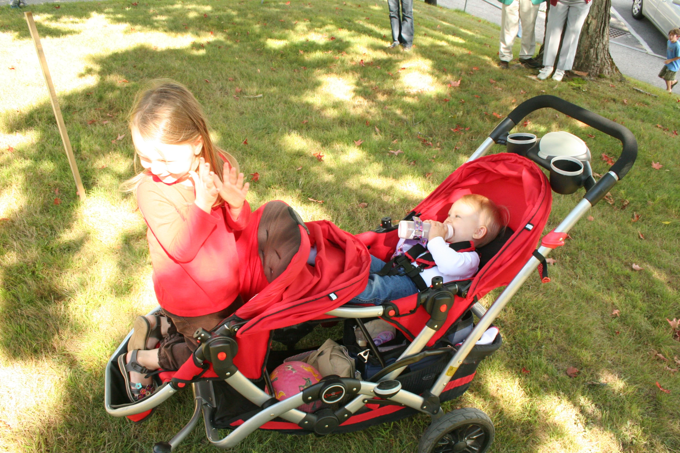 a child sits in a stroller while another child talks on the phone