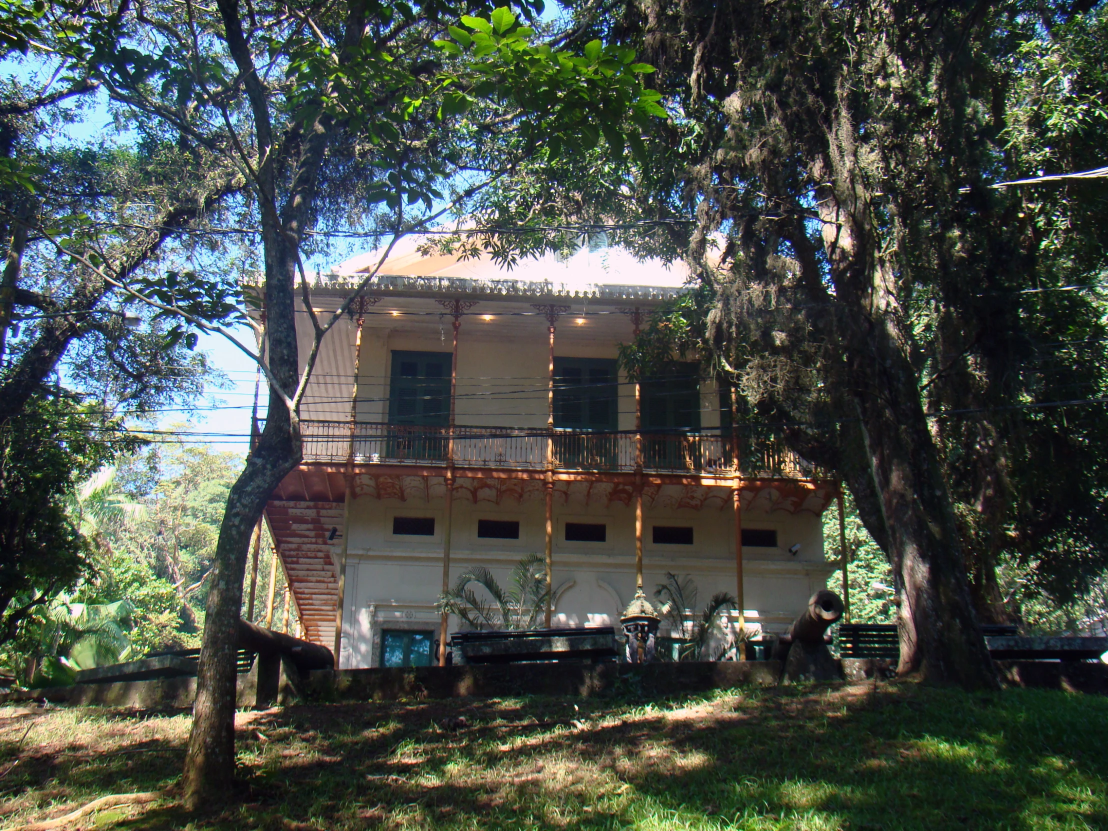 a tall white building with three storys surrounded by trees