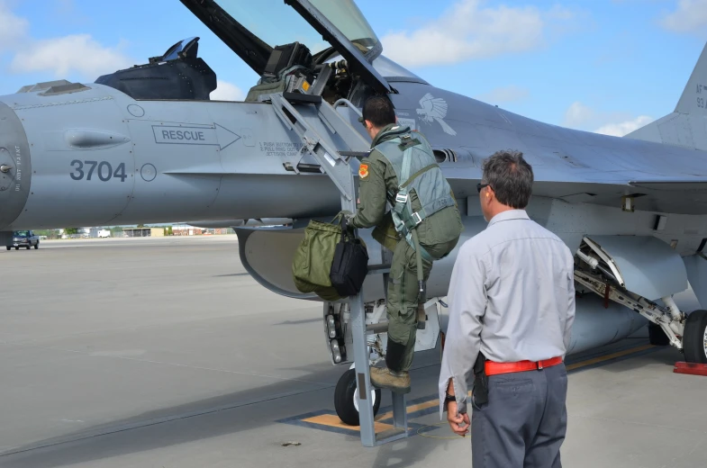 two soldiers loading gear onto a fighter jet