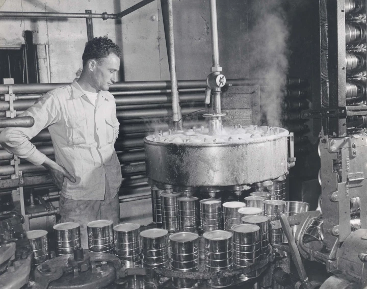 a man working in a large factory with metal containers