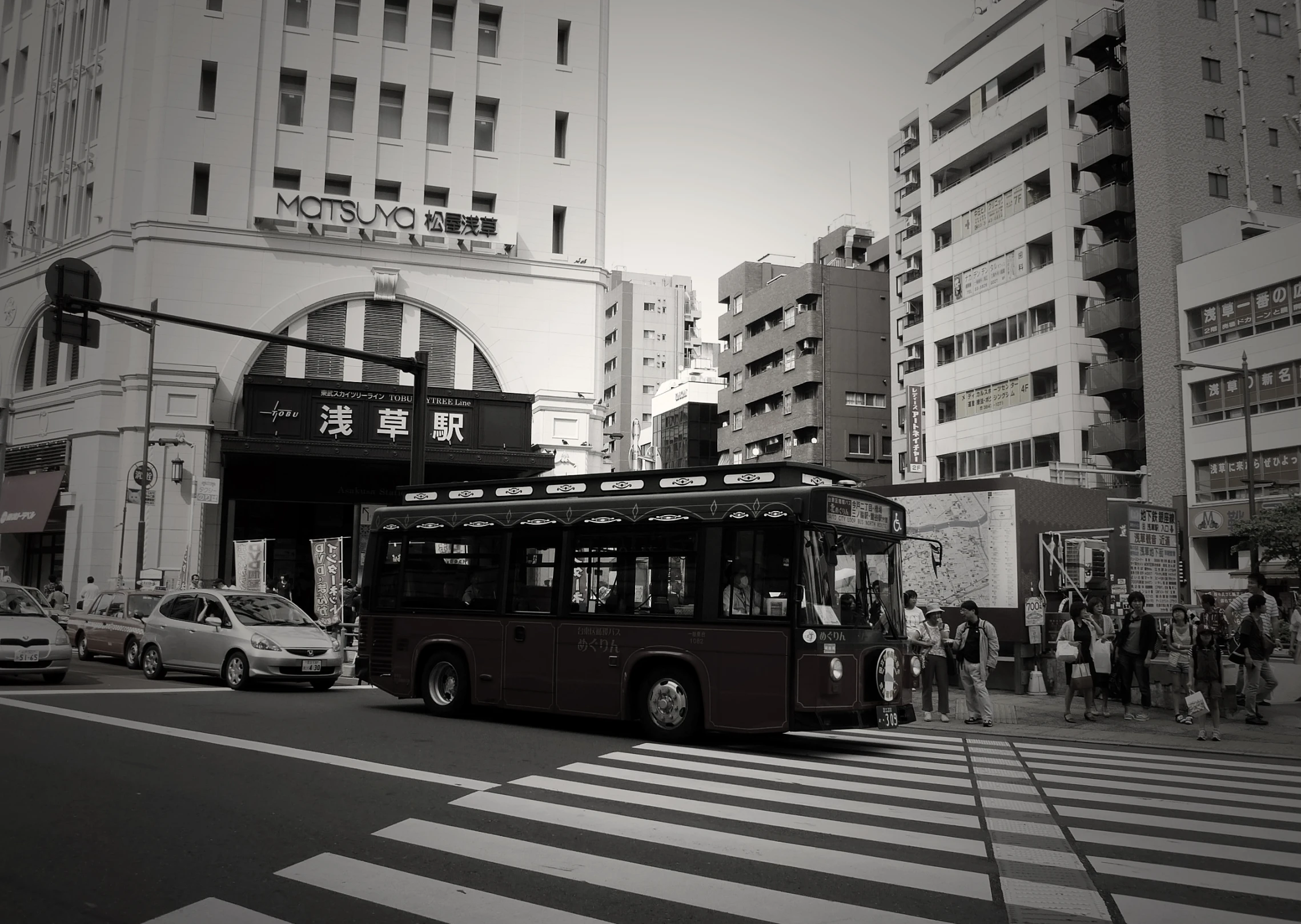 a city bus driving down the street with people waiting for it