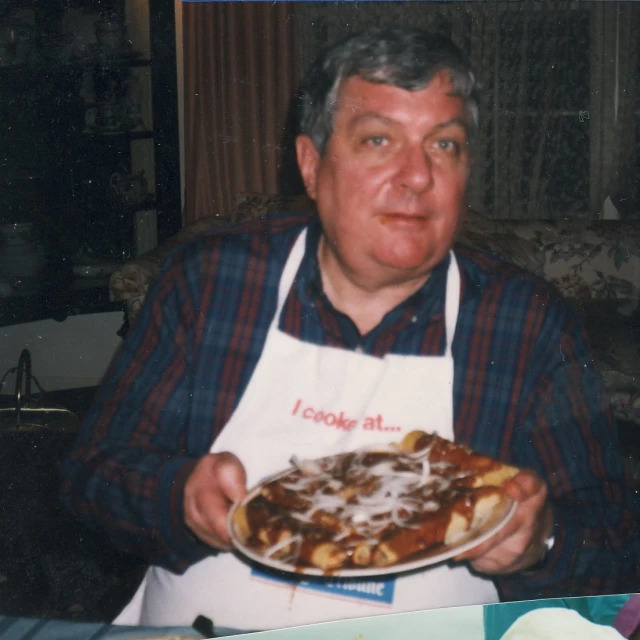 a man holding a pizza covered in cheese