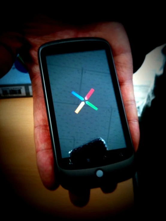 the hand is holding a black cell phone with several colored stickers on it