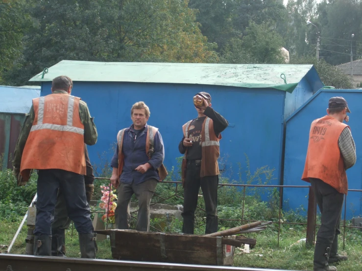 a group of men stand near a building while wearing construction gear