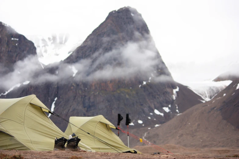 two yellow tents pitched in the dirt near some mountains