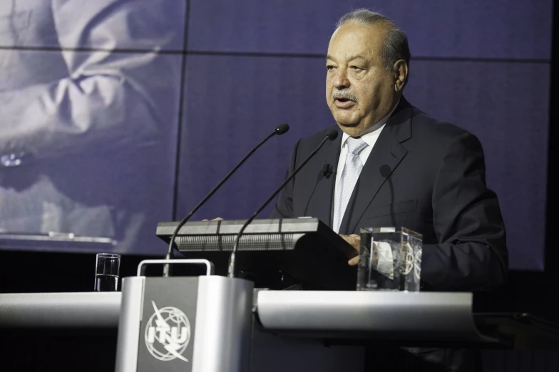 a man wearing a suit and tie speaking on a podium