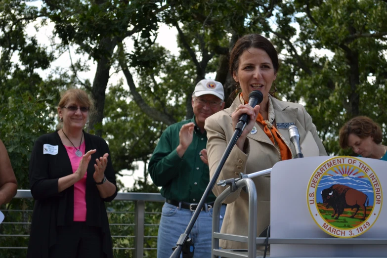 a woman is speaking in front of several people