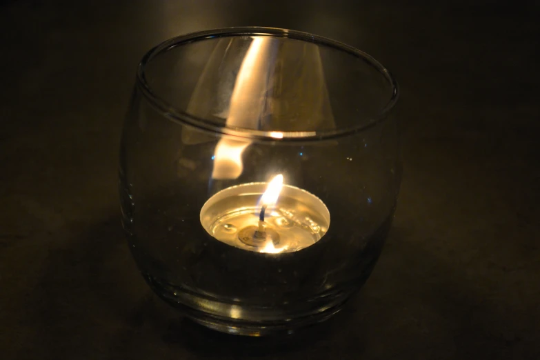 lit candle on top of a glass filled with water