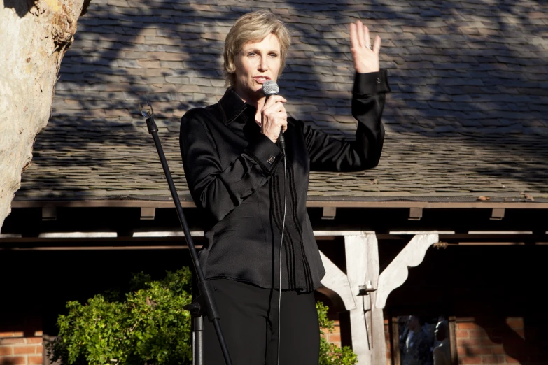 woman holding microphone near her face standing next to a rock formation