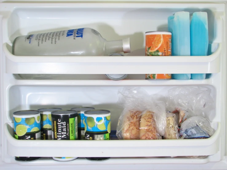 the side of a refrigerator with two shelves containing drinks, juice and food