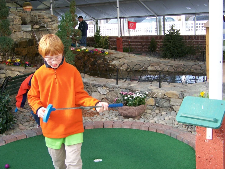 a boy standing on a putting green putting his putt in the hole