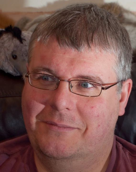 a close up of a person with glasses in front of a bear