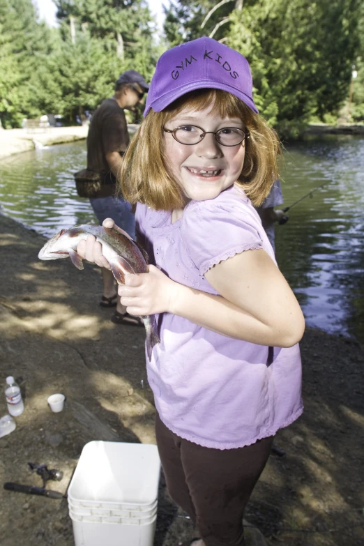 a small girl holds a fish on a small boat