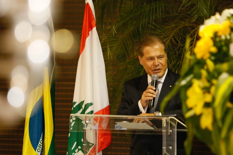 a man speaking on a podium next to flags