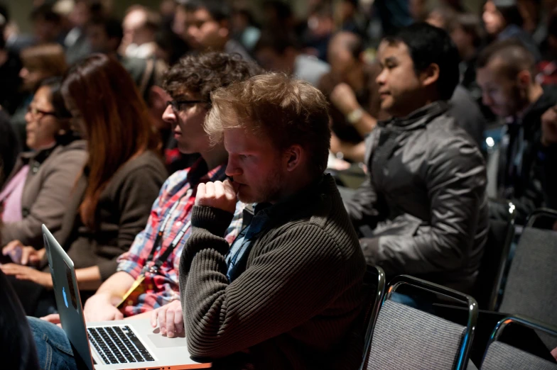 a group of people sitting in chairs with their laptops open