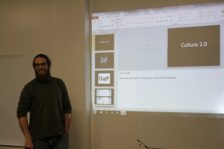 a man stands in front of a projector while a person looks on
