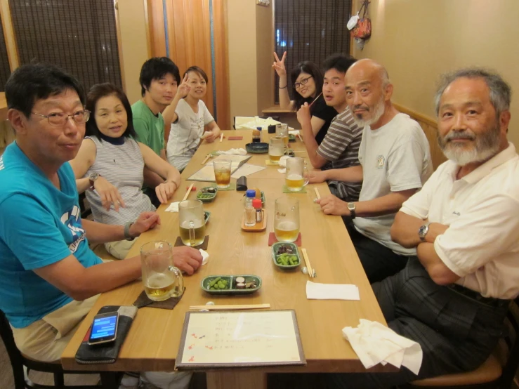 people are sitting around a long wooden table having lunch