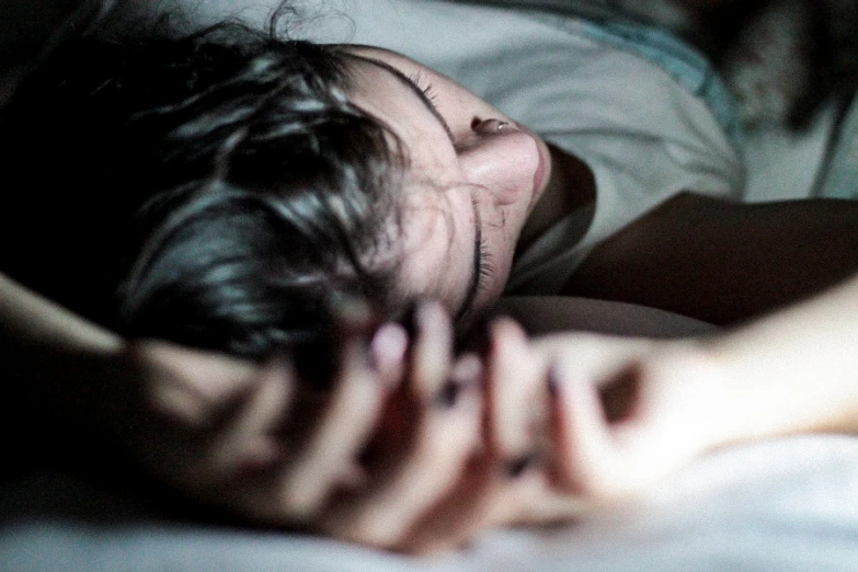 a man sleeping in bed on his back and looking at the camera