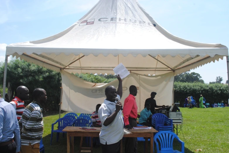 a crowd of people standing around a table under a tent