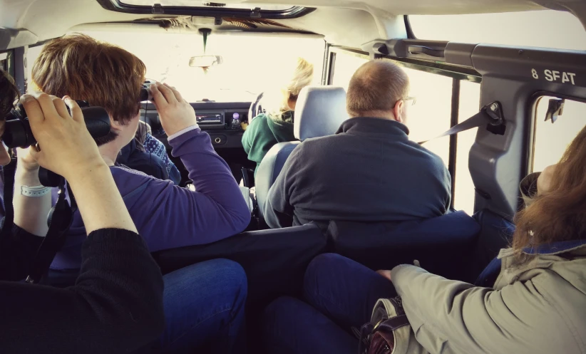 several people sit inside a bus looking at their surroundings