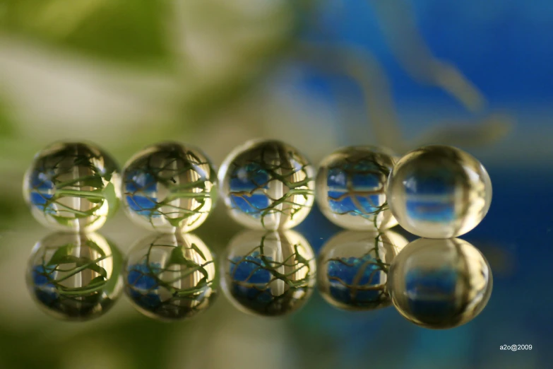 several glass marbles reflecting leaves and sky