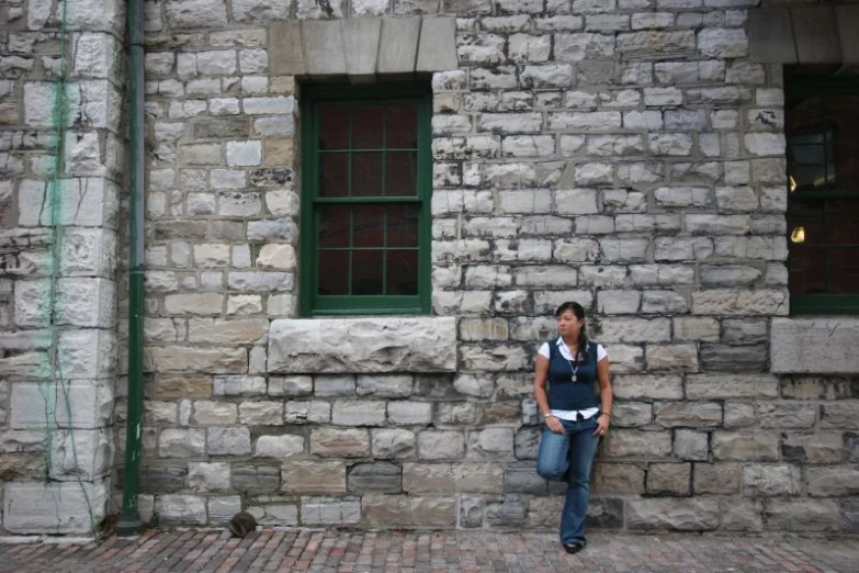 the girl is posing for the camera in front of a stone building