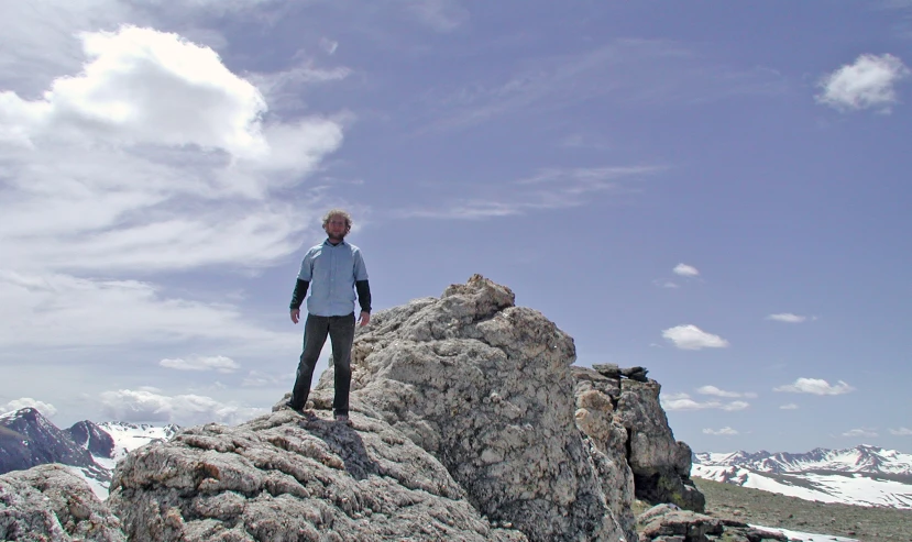 a man standing on the top of a hill with some snow