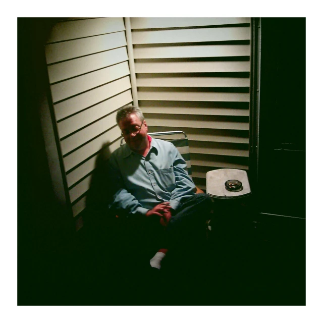 man sitting in chair next to window in home