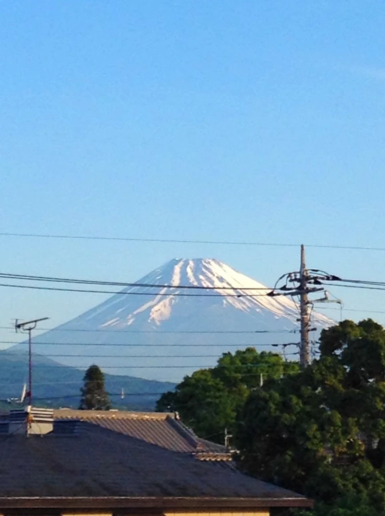 a house with trees and a large snow - capped mountain in the distance