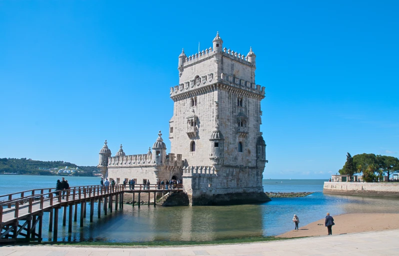 a very tall tower by the water with some people walking up it