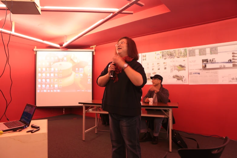 a man in a black shirt standing in front of a projector screen