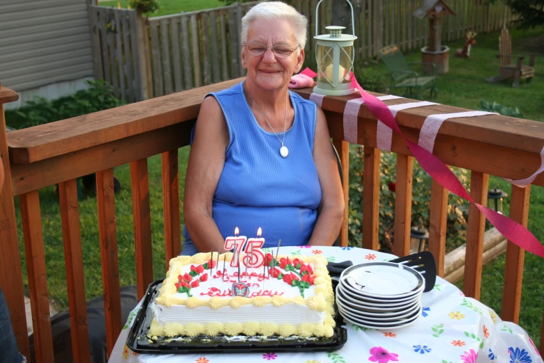 the lady is sitting on the deck with her birthday cake