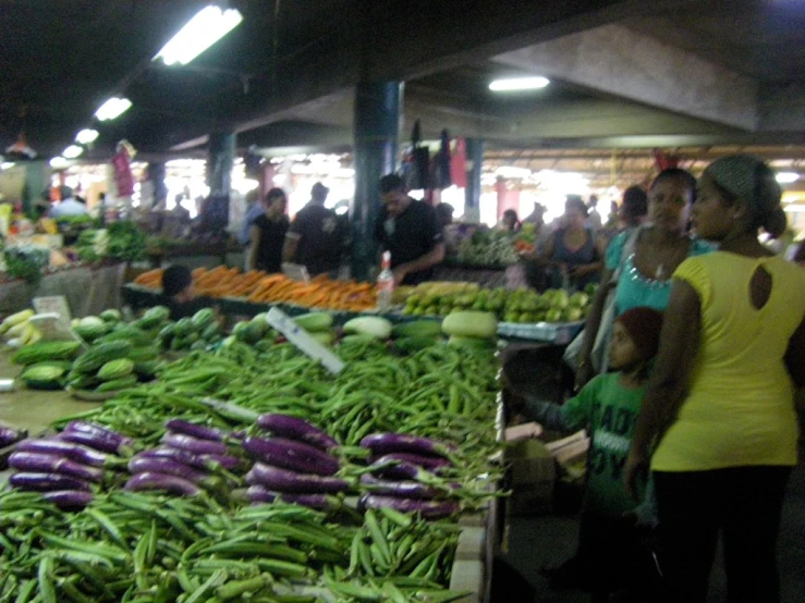group of people at outdoor market looking at vegetables