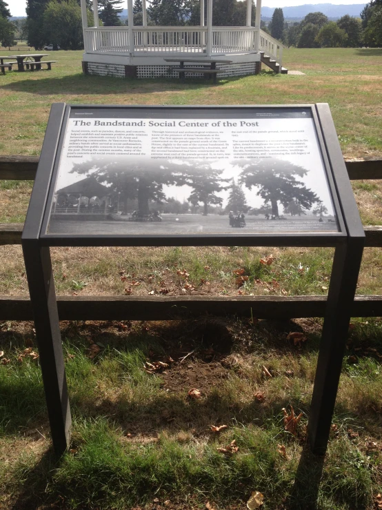 a white wooden gazebo sitting in the middle of a park