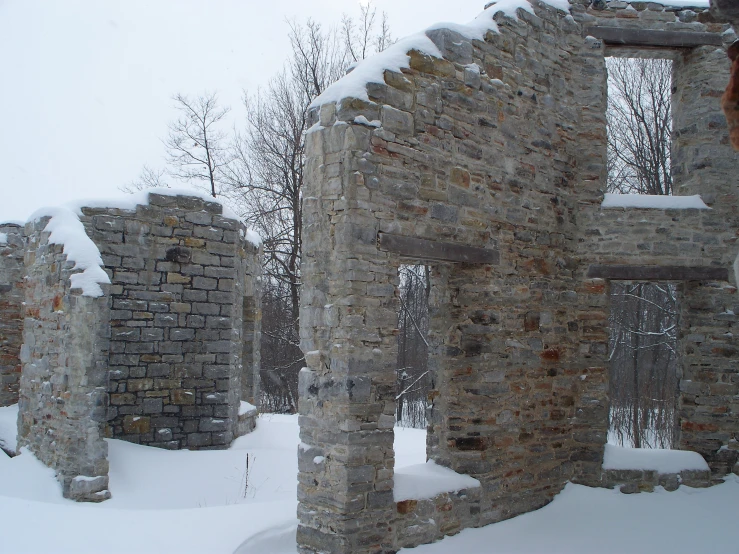 an old stone structure surrounded by snow in the woods